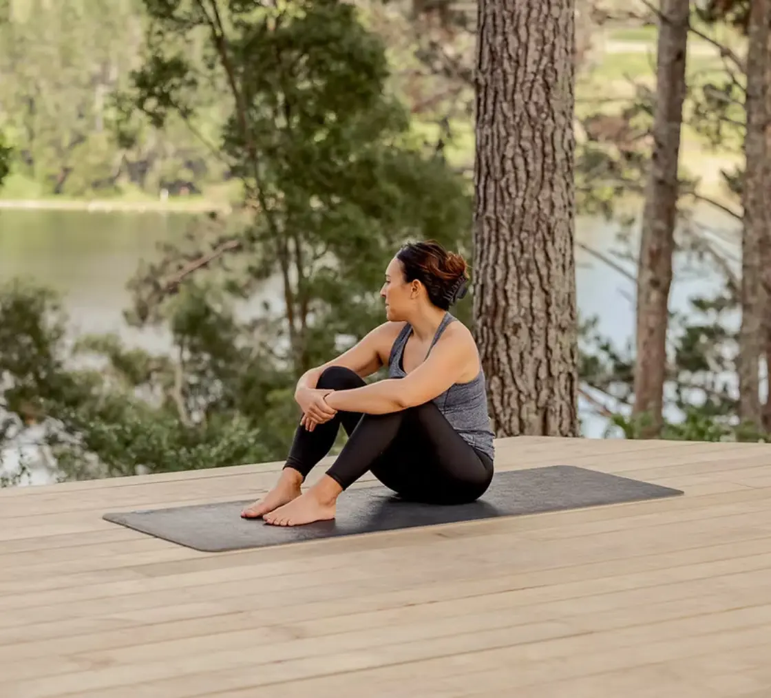 Guest relaxing on a yoga mat beside the lake